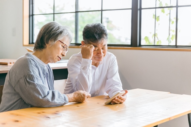 テーブルで相談する老夫婦 | 緑のタニムラ